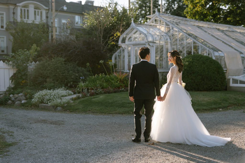 Bride in tulle ballgown wedding dress with cathedral veil walking with groom at outdoor wedding venue