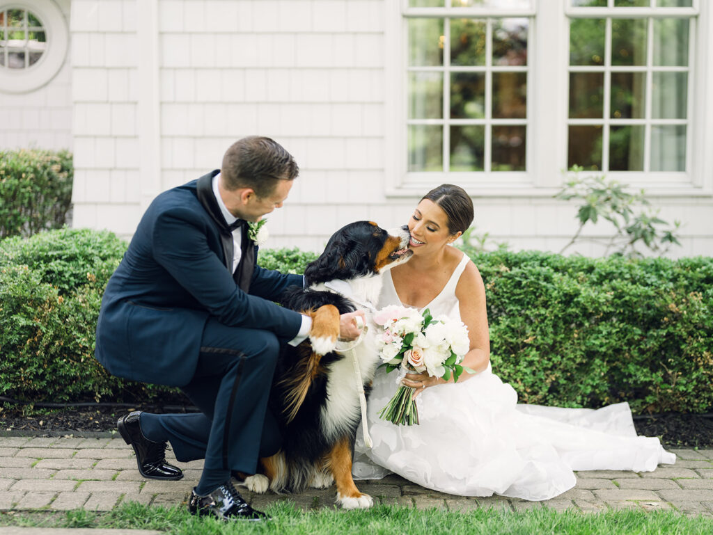 A bride and groom sit with their dog on their wedding day. The bride wears an A-line wedding dress by Lea-Ann Belter Bridal.