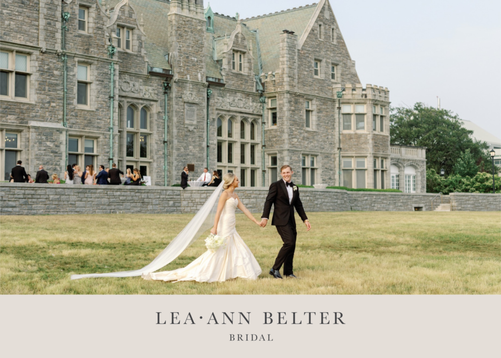 A bride and groom walking together across a lawn with a mansion in the background