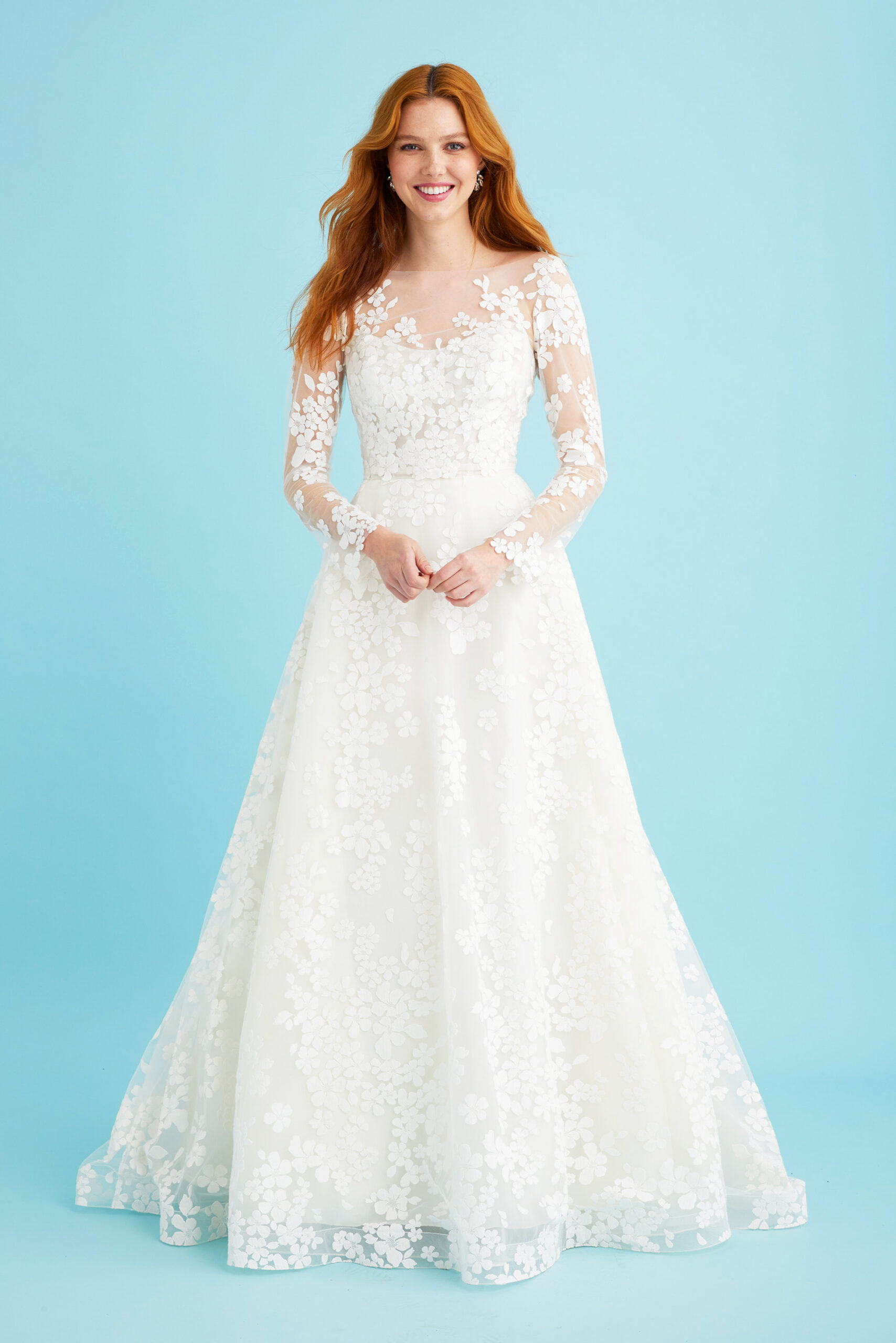 Full-length image of the Coralie gown styled with its matching jacket. This floral corset wedding gown by Toronto bridal gown designer Lea-Ann Belter features a dreamy embroidered net overlay, full skirt, and romantic translucent train.