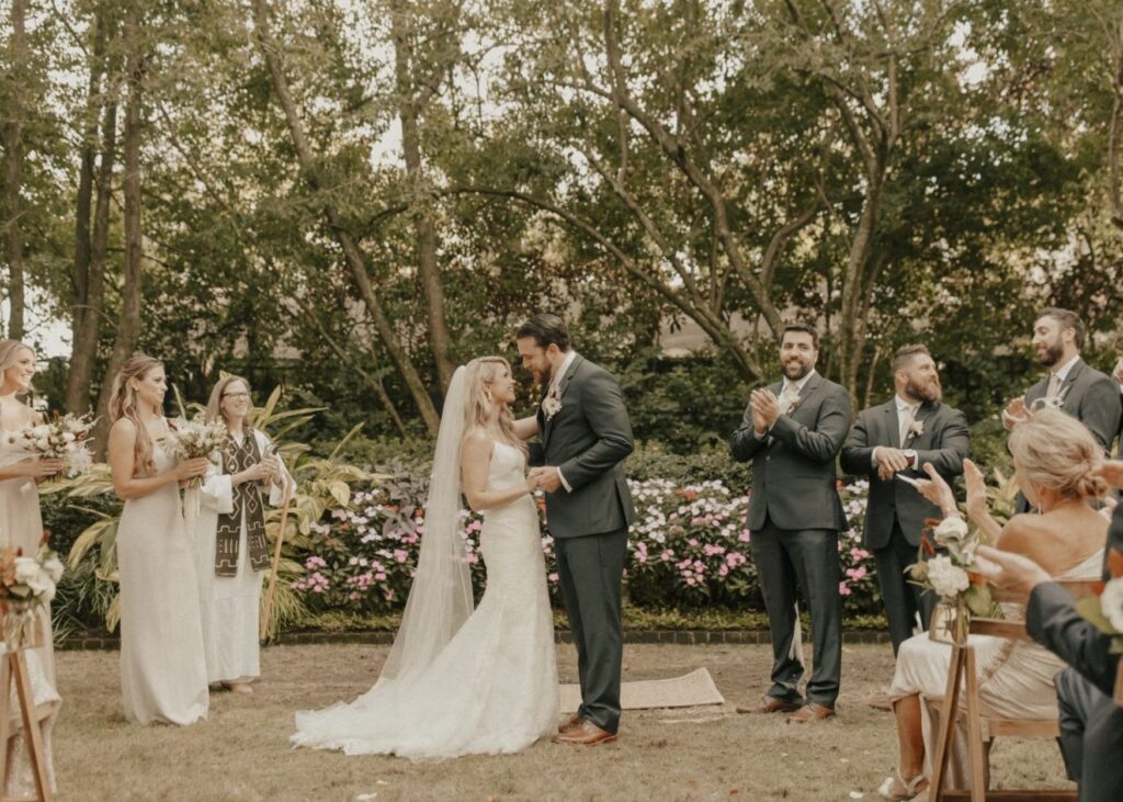 A bride and groom kiss during thier outdoor ceremony. The bride wearing a fit & flare wedding dress by Lea-Ann Belter Bridal