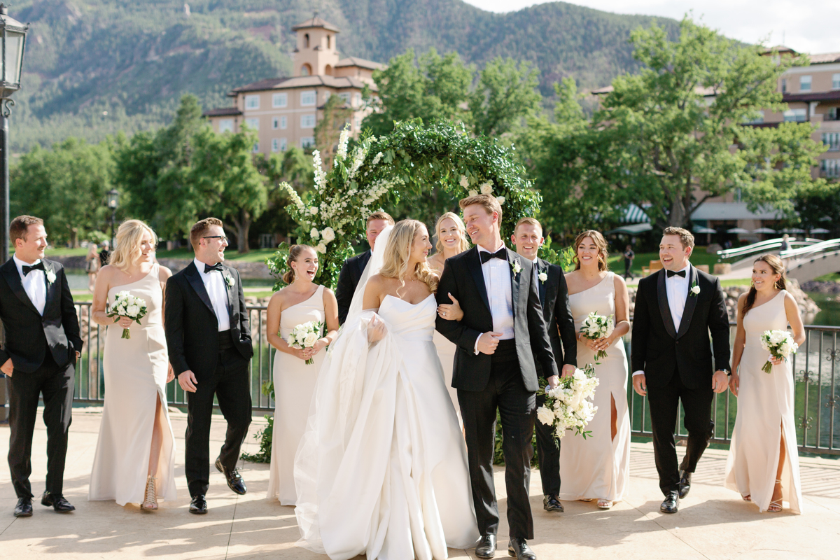 Real bride wearing elegant ball gown wedding dress celebrates with bridal party at outdoor mountain wedding venue
