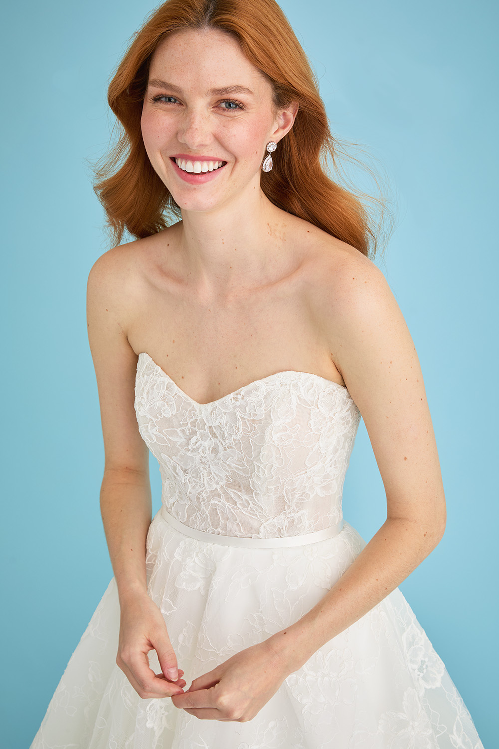 Close-up of the bride in the Lea-Ann Belter Bridal Jane sweetheart lace wedding dress, focusing on the semi-sheer lace bodice and curved neckline. The soft floral pattern and satin waistband add a romantic finish.