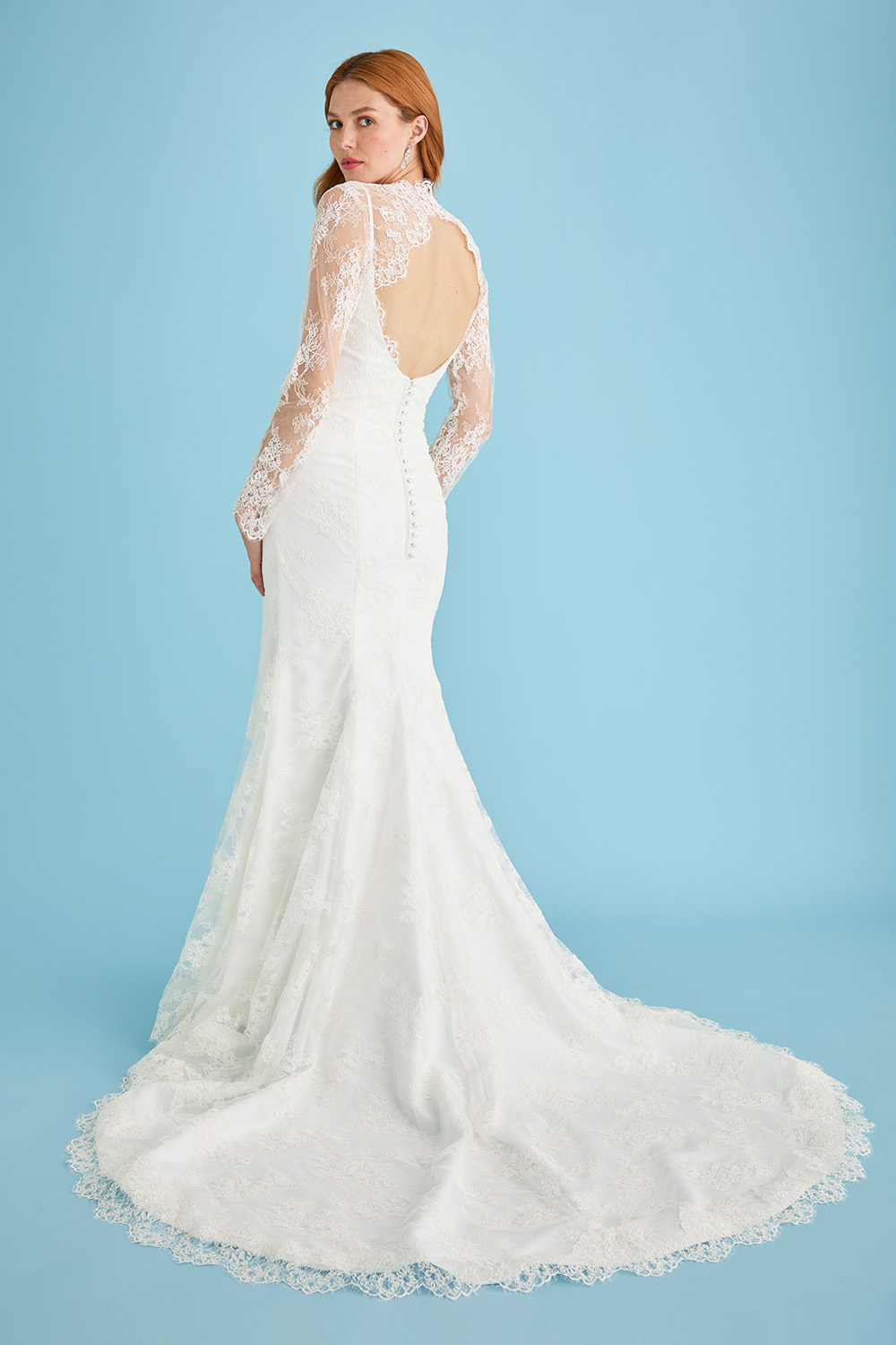 Bride in the Lea-Ann Belter Bridal Kitty gown styled with a sheer lace bridal jacket. The jacket adds long sleeves, a high neckline, and a dramatic keyhole back over the gown’s open back silhouette.
