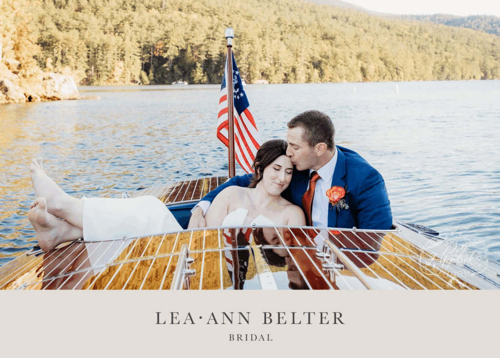 Bride and groom relaxing on a wooden boat after their Lake George wedding, the bride in a strapless Lea-Ann Belter gown and the groom in a blue suit with red tie.
