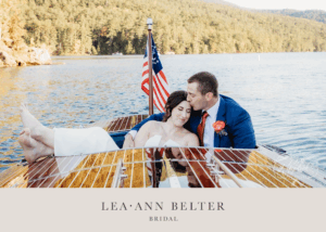 Bride and groom relaxing on a wooden boat after their Lake George wedding, the bride in a strapless Lea-Ann Belter gown and the groom in a blue suit with red tie.