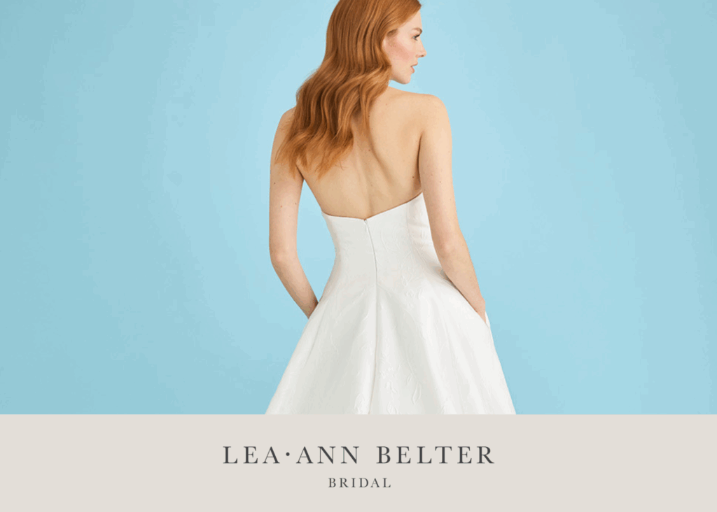 Bride in a strapless jacquard wedding dress with pockets, standing against a blue background.