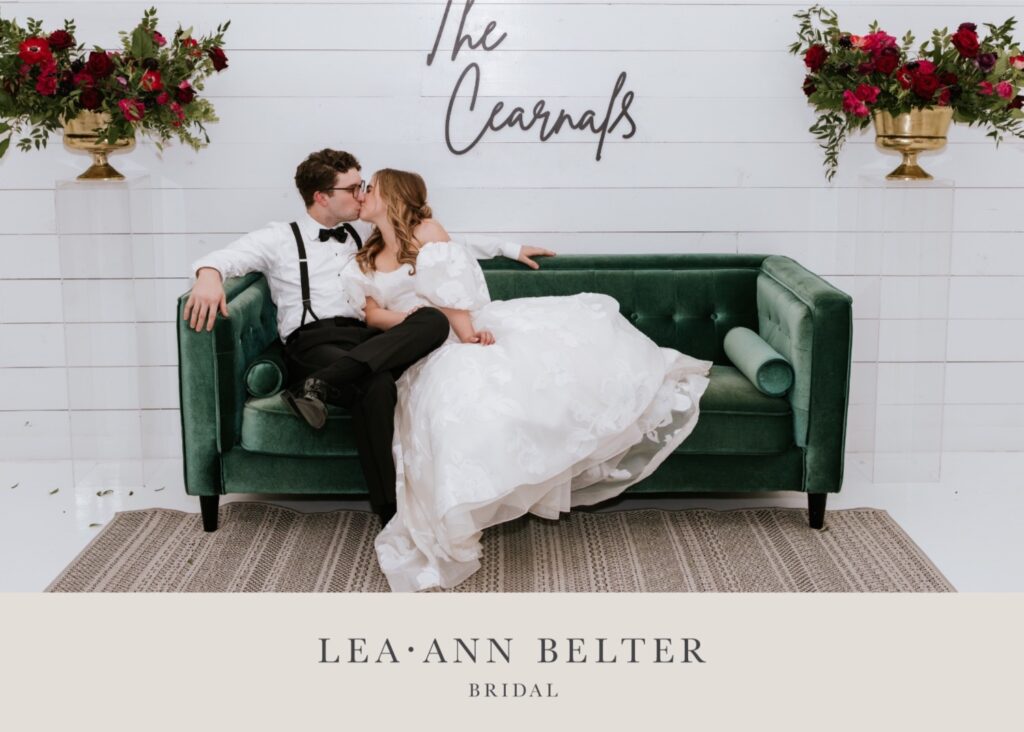 Bride Macy in Lea-Ann Belter's Esperanza gown kissing groom Shane on a green velvet couch at The RoseMary venue