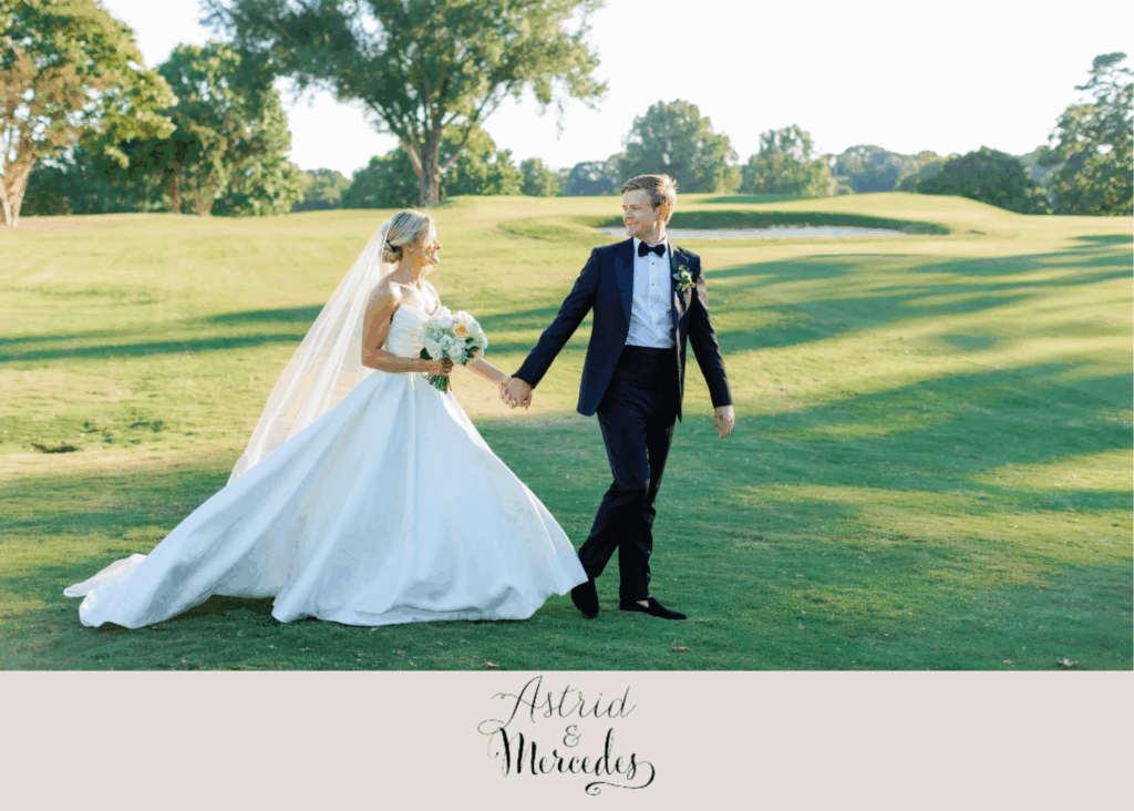 Bride and groom walk hand in hand across the green lawn at Forsyth Country Club, the bride in a classic strapless ball gown with a flowing veil and bouquet, and the groom in a black tuxedo with bow tie.