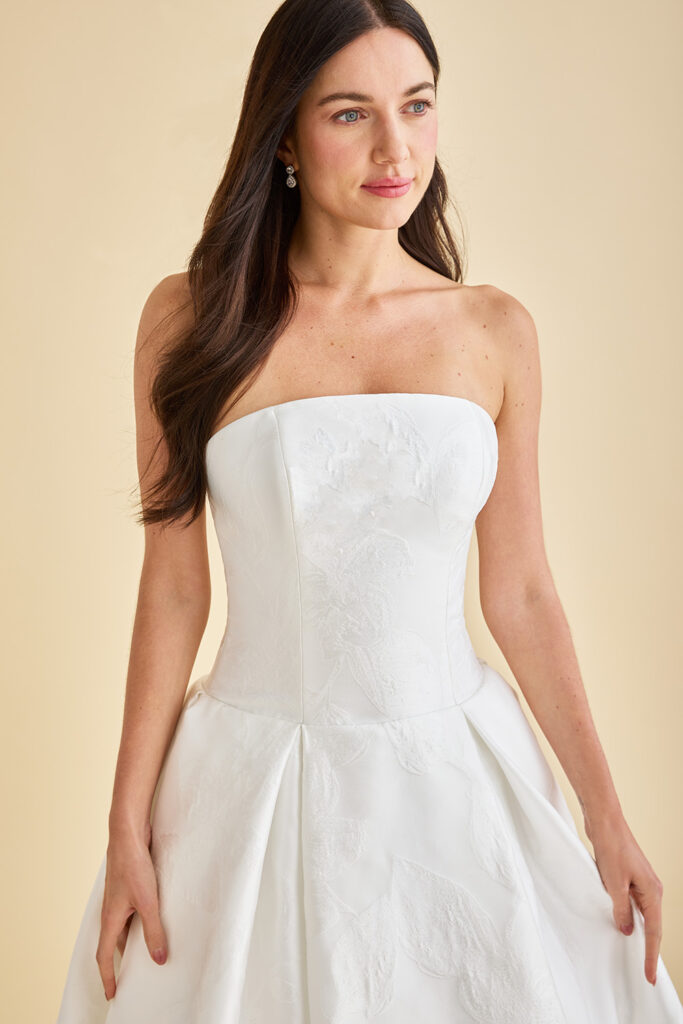 Nouvelle, a jacquard drop waist ball gown with strapless neckline, floral pattern, and pleated skirt.