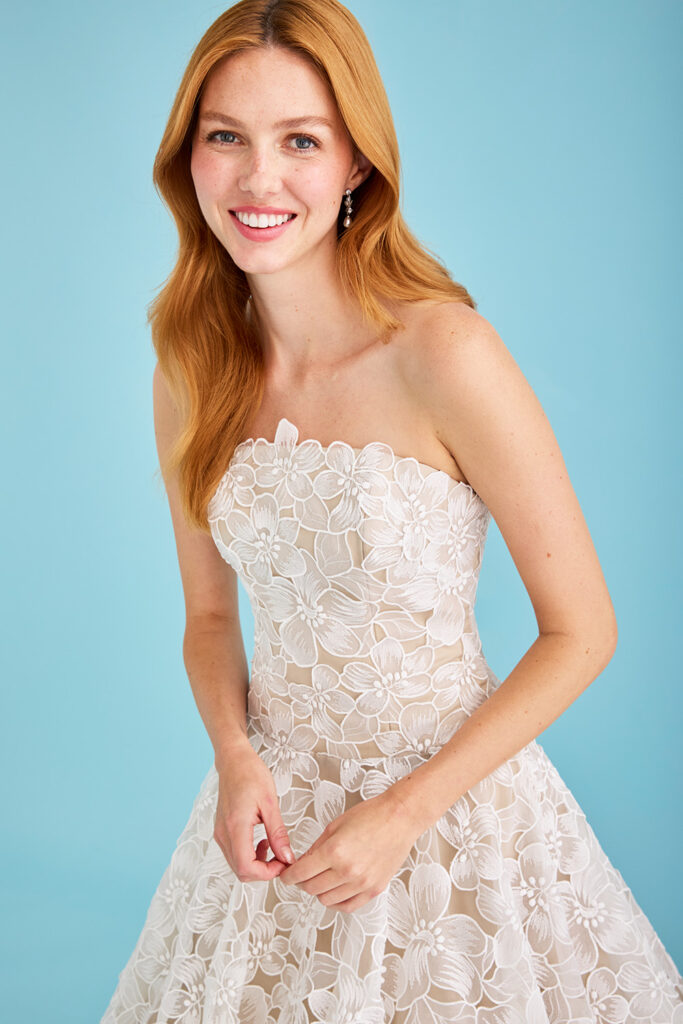 Close up of a bride in Luanne, a strapless drop waist wedding ball gown overlaid in laser-cut organza anemone flowers by Lea-Ann Belter Bridal.
