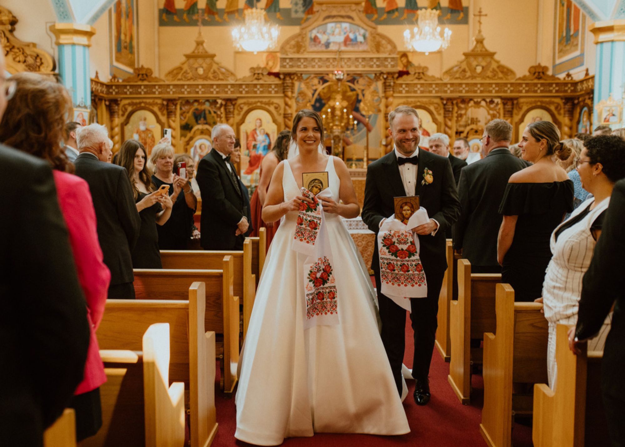 Erica and Thomas walk down the aisle during their Ukranian orthodox wedding ceremony. Erica is wearing a v-neck ball gown wedding dress by Lea-Ann Belter Bridal