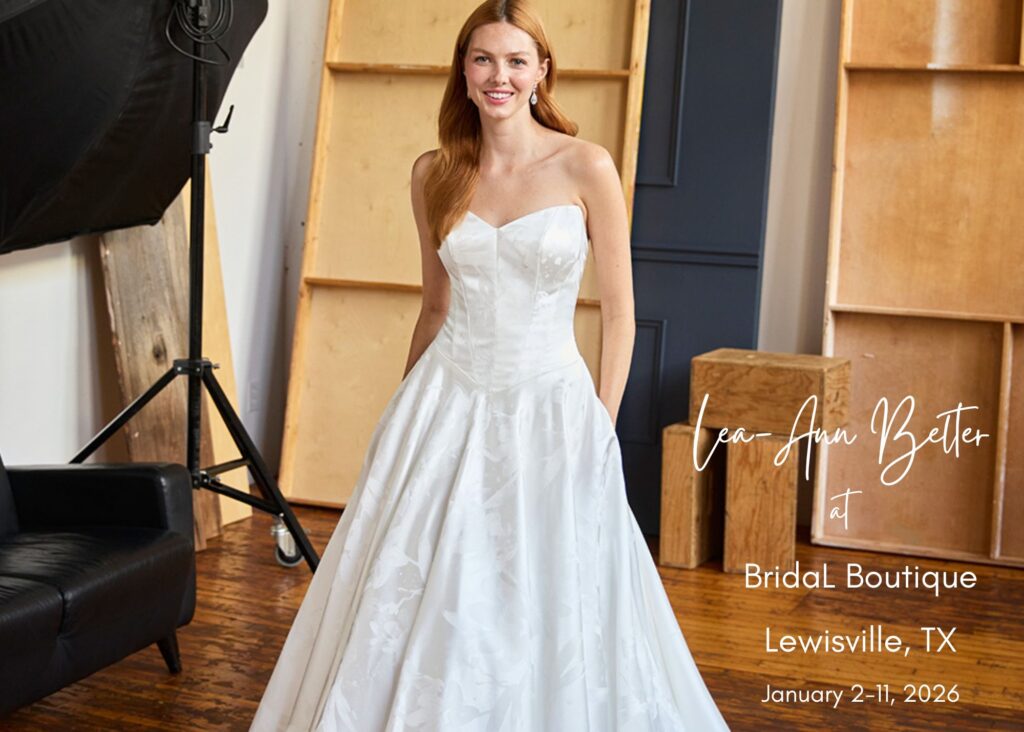 A bride stands in a modern, wood-walled photography studio, hands in the pockets of her strapless sweetheart ball gown wedding dress. Text reads, Bridal Boutique trunk show in Lewisville, Texas, January 2-11, 2026