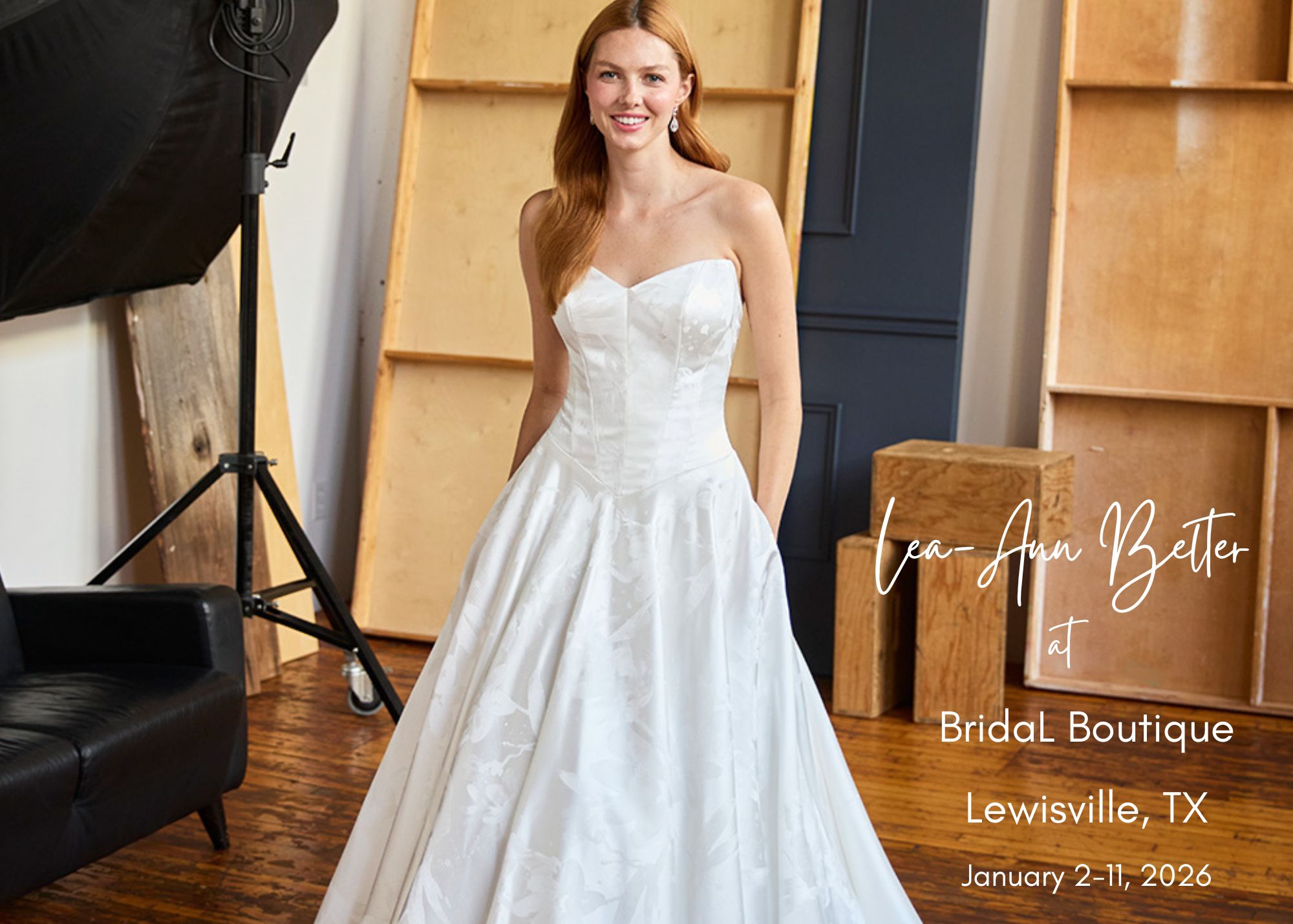 A bride stands in a modern, wood-walled photography studio, hands in the pockets of her strapless sweetheart ball gown wedding dress. Text reads, Bridal Boutique trunk show in Lewisville, Texas, January 2-11, 2026