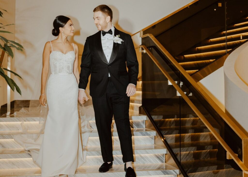 Bride in sleek wedding dress with Swarovski crystal straps and groom in black tuxedo at Ritz-Carlton Toronto wedding