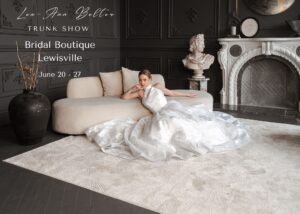 A dramatic photo of a bride reclining on a white couch wearing a halter neck wedding dress with its full skirt spread around her. Text reads: Lea-Ann Belter Bridal Keep sake Collection Trunk Show Bridal Boutique Lewisville June 20-27