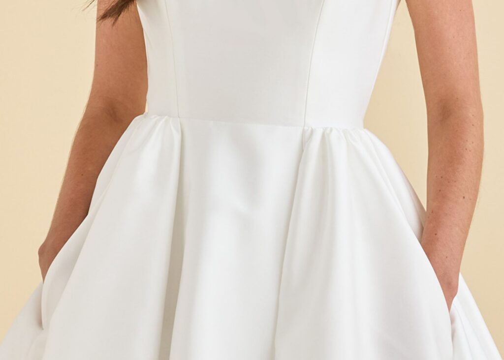 Bride with hands in the hidden pockets of the Belle ball gown wedding dress by Astrid & Mercedes, in structured ivory mikado.