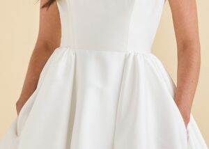 Bride with hands in the hidden pockets of the Belle ball gown wedding dress by Astrid & Mercedes, in structured ivory mikado.