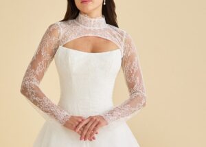 The cat's eye neckline peeks out from under a sheer Chantilly lace topper with long sleeves